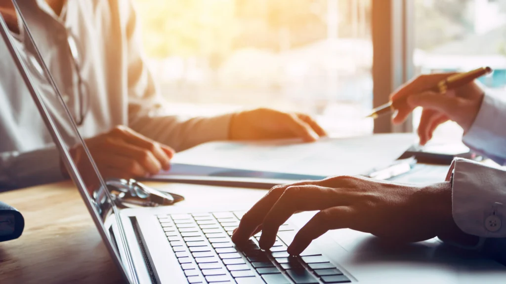 A medical provider sitting with patient at computer looking at their website speaking
